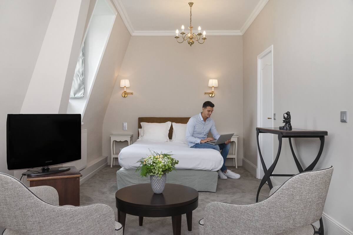 A hotel room with a bed, a TV, a desk, and a chair.