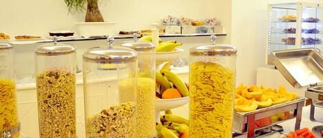 Un bufé con diversas opciones de comida, como cereales, frutas y pasteles.
