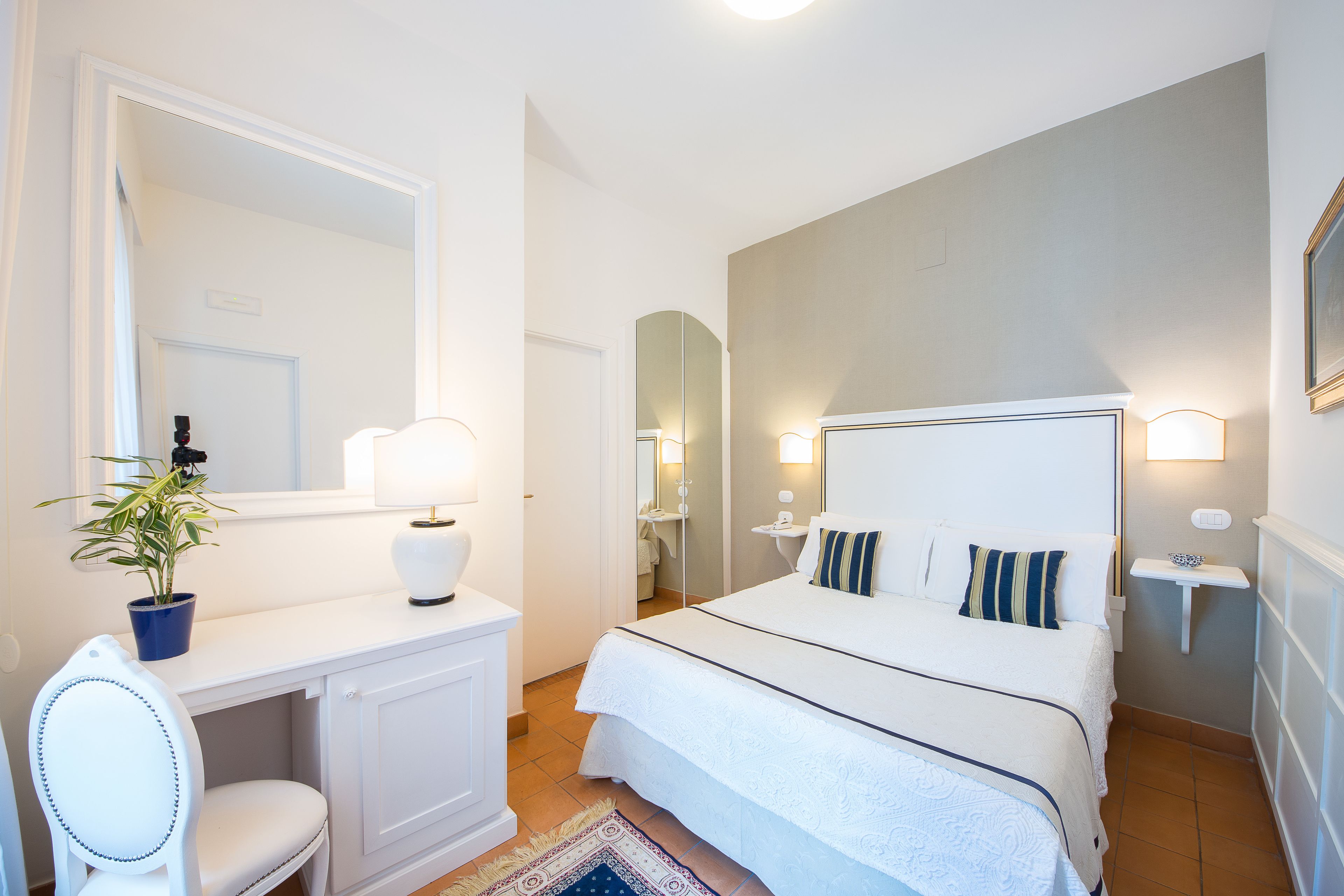 Una camera da letto con un letto, un comodino, una lampada, una sedia e una pianta in vaso.