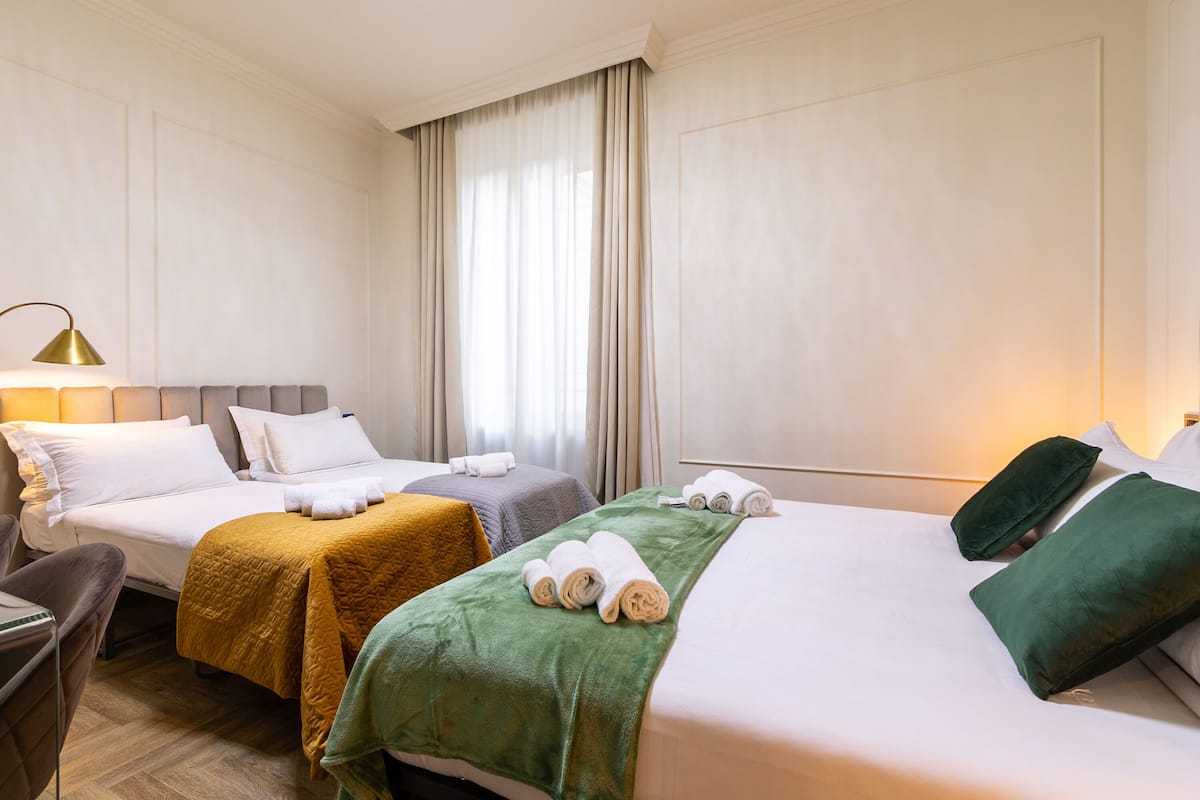 Ein Hotelzimmer mit zwei Betten, einem Schreibtisch und einem Sessel.