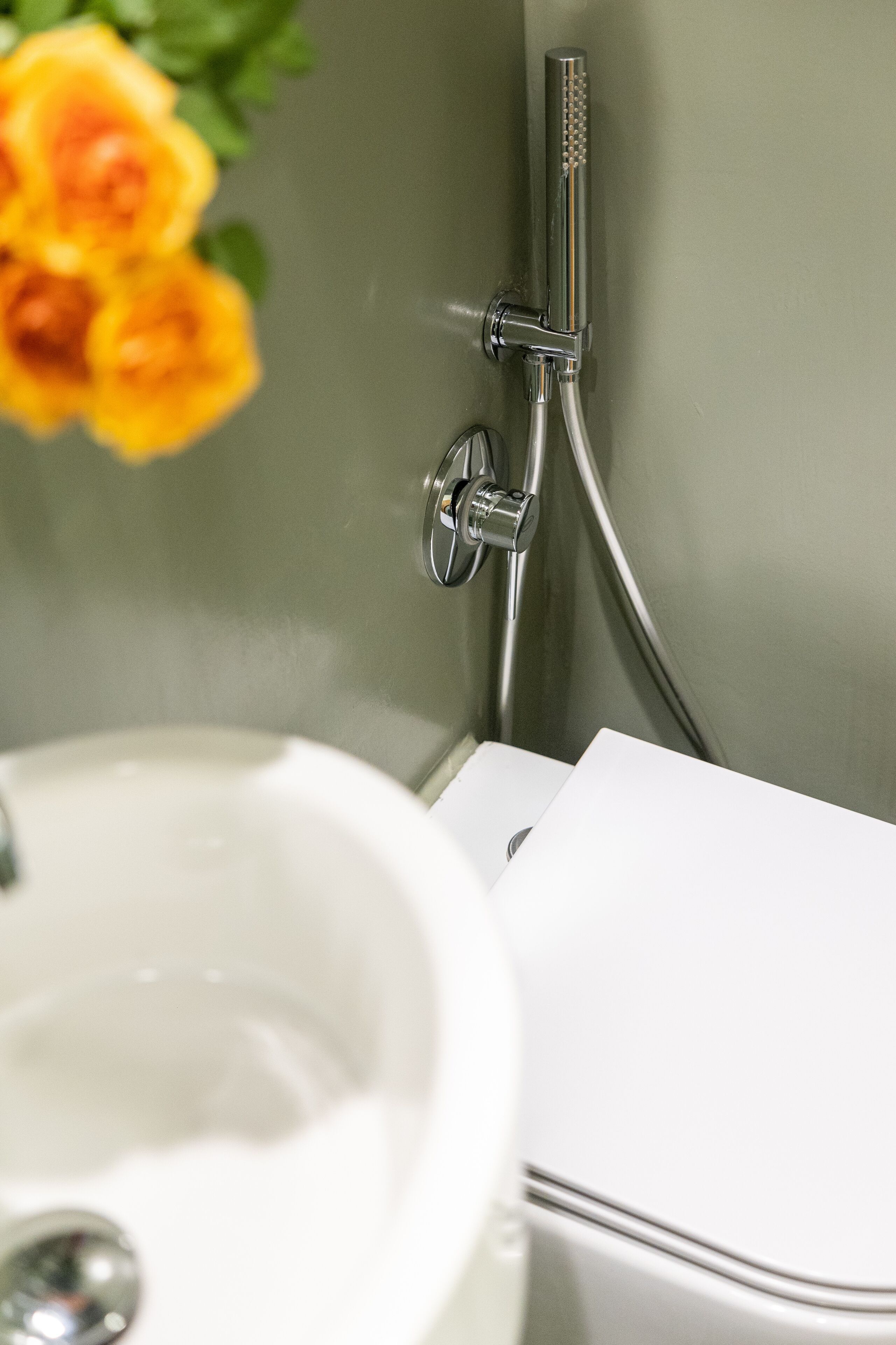 Une salle de bain avec un lavabo blanc, une pomme de douche et des toilettes.