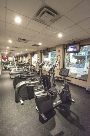 Un gimnasio con cintas de correr, elípticas y pelotas de ejercicio.