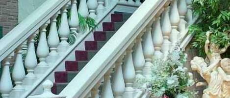 Una gran escalera con barandales ornamentales, una balaustrada de piedra y una estatua en la parte superior.