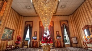 A grand room with a large chandelier, ornate furniture, and a view of a bridge.