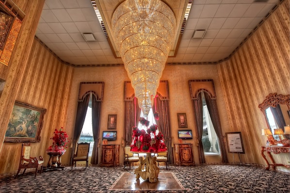 Una sala elegante con una gran araña, muebles ornamentados y vistas a un puente.