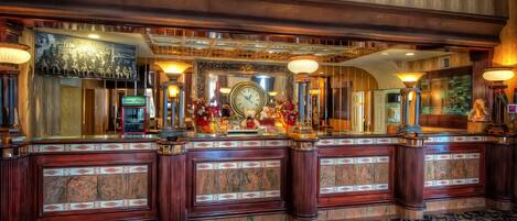 A lobby with a reception desk, a large clock, and a decorative mirror.