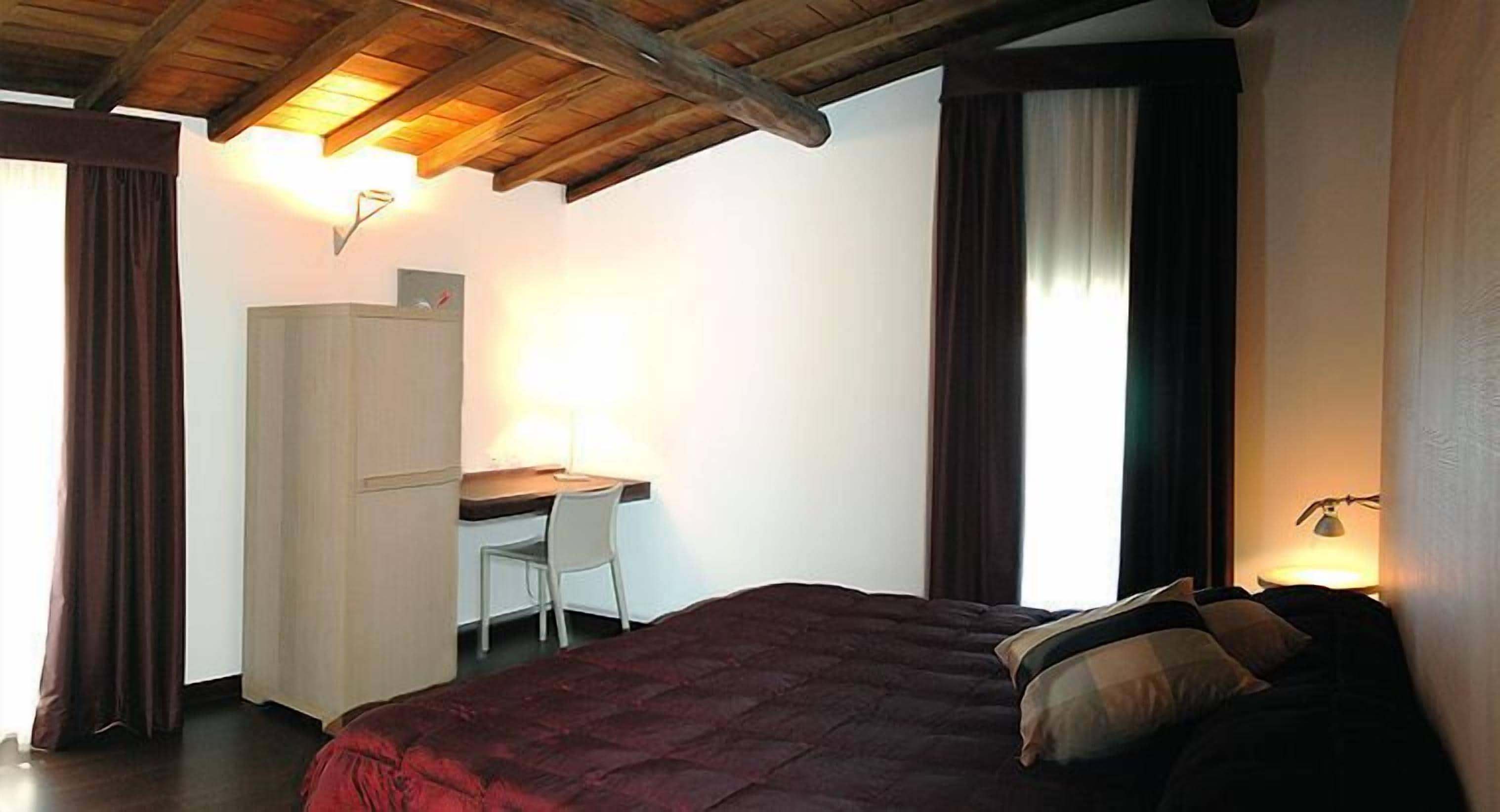 A bedroom with a bed, a desk, and a wardrobe.