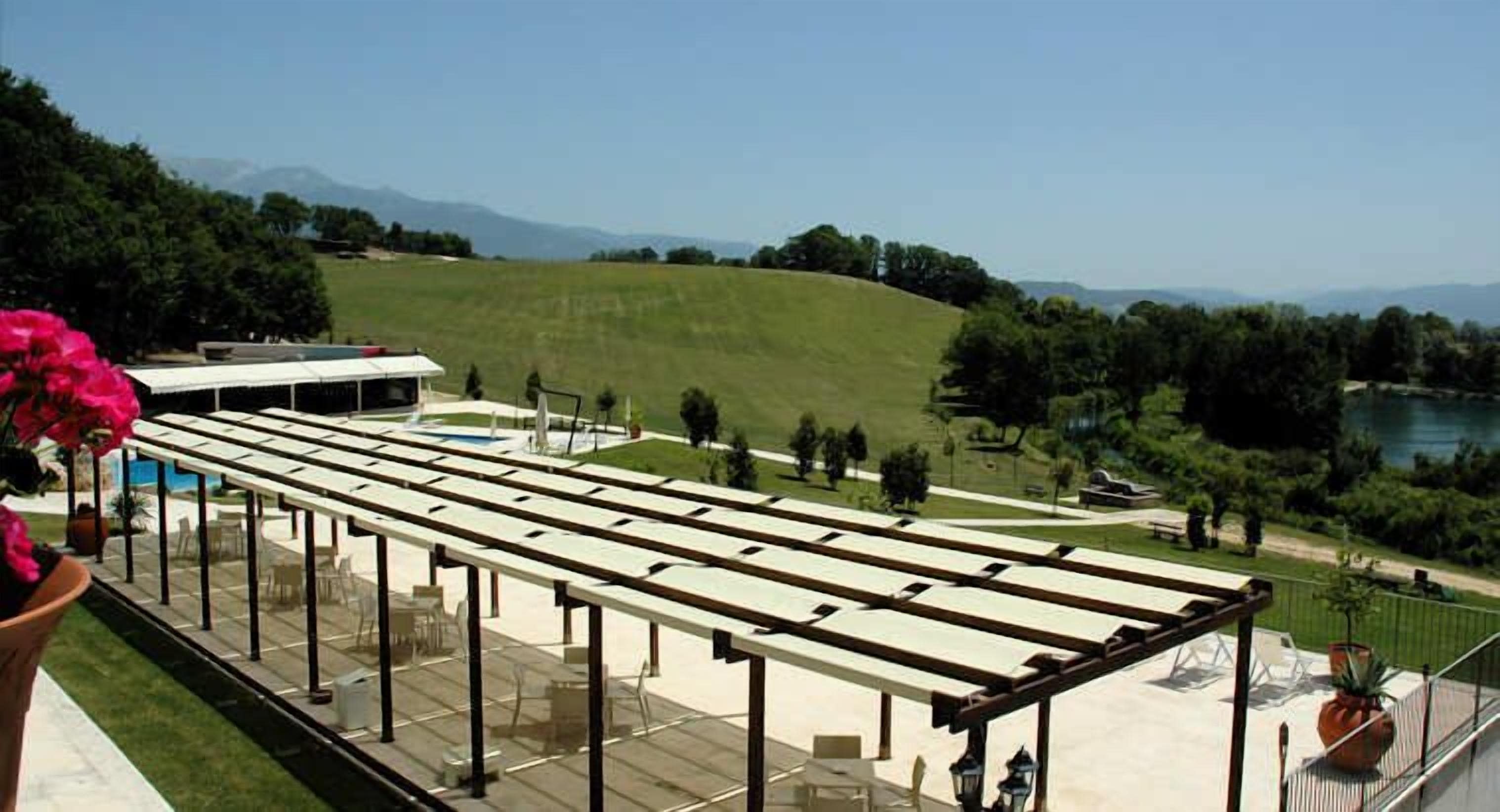 An outdoor terrace with a pergola, seating, and a view of a park and mountains.