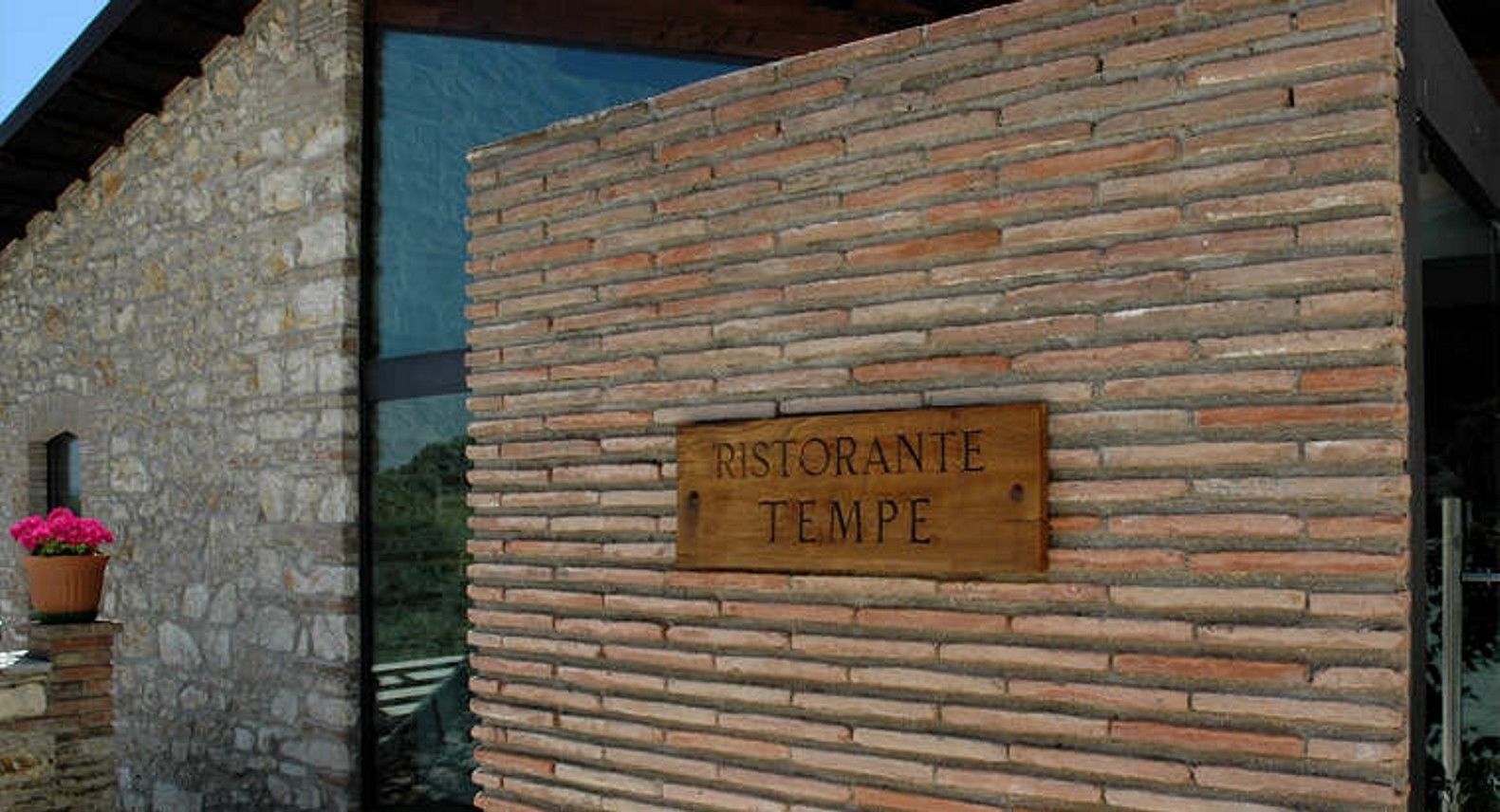 Fachada de un edificio rústico con un letrero de madera que dice "RISTORANTE TEMPE".