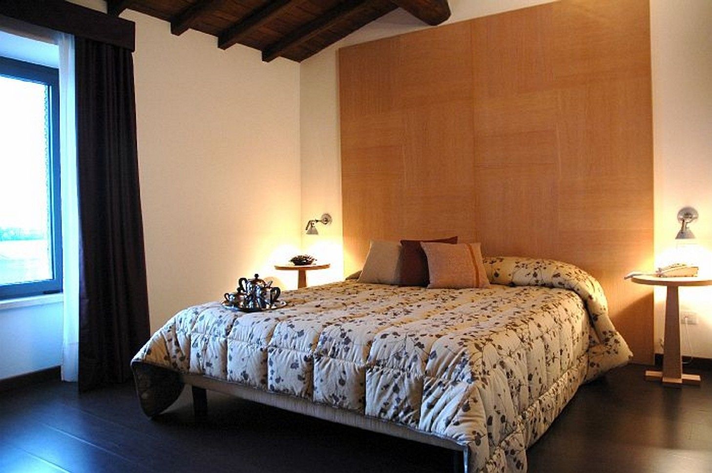 Une chambre à coucher avec un lit, une table de chevet, une lampe et une fenêtre avec des rideaux.