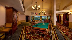 A pool table in a hotel lobby with a patterned carpet, seating area, and chandeliers. - Disney's Saratoga Springs Resort & Spa (Lake Buena Vista)