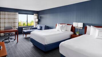 A hotel room with two beds, a desk, and a chair.