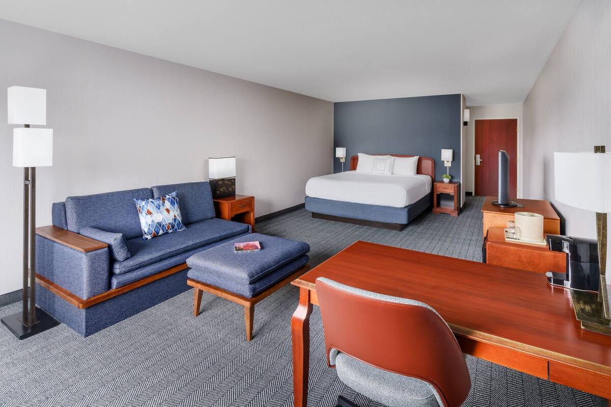 Een hotelkamer met een bed, een slaapbank, een bureau en een stoel.