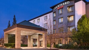 Ein Courtyard Marriott Hotel mit überdachter Einfahrt, mehreren Etagen und einer gut beleuchteten Fassade.