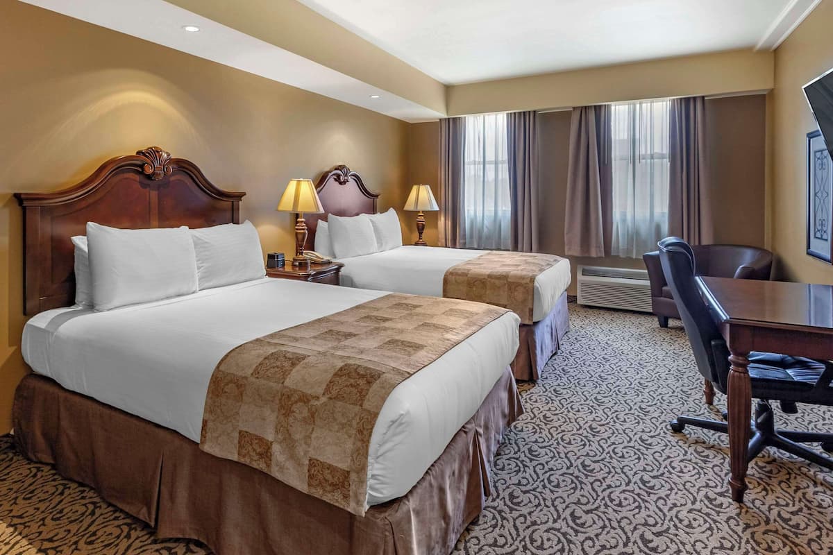 Une chambre d’hôtel avec deux lits, un bureau et une chaise.