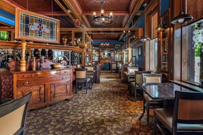 Eine Bar mit Holzkubaturen, einem gemusterten Teppich und einem Buntglasfenster.