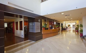 A hotel lobby with a reception desk, a clock, and a sign indicating a car service area. - Mercure Rome Leonardo da Vinci Airport (Fiumicino)