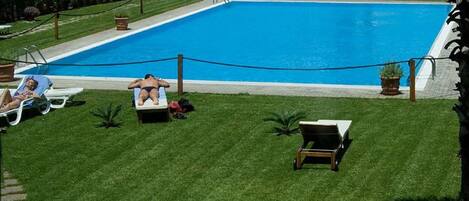 Une piscine avec des chaises longues et une personne qui prend un bain de soleil.