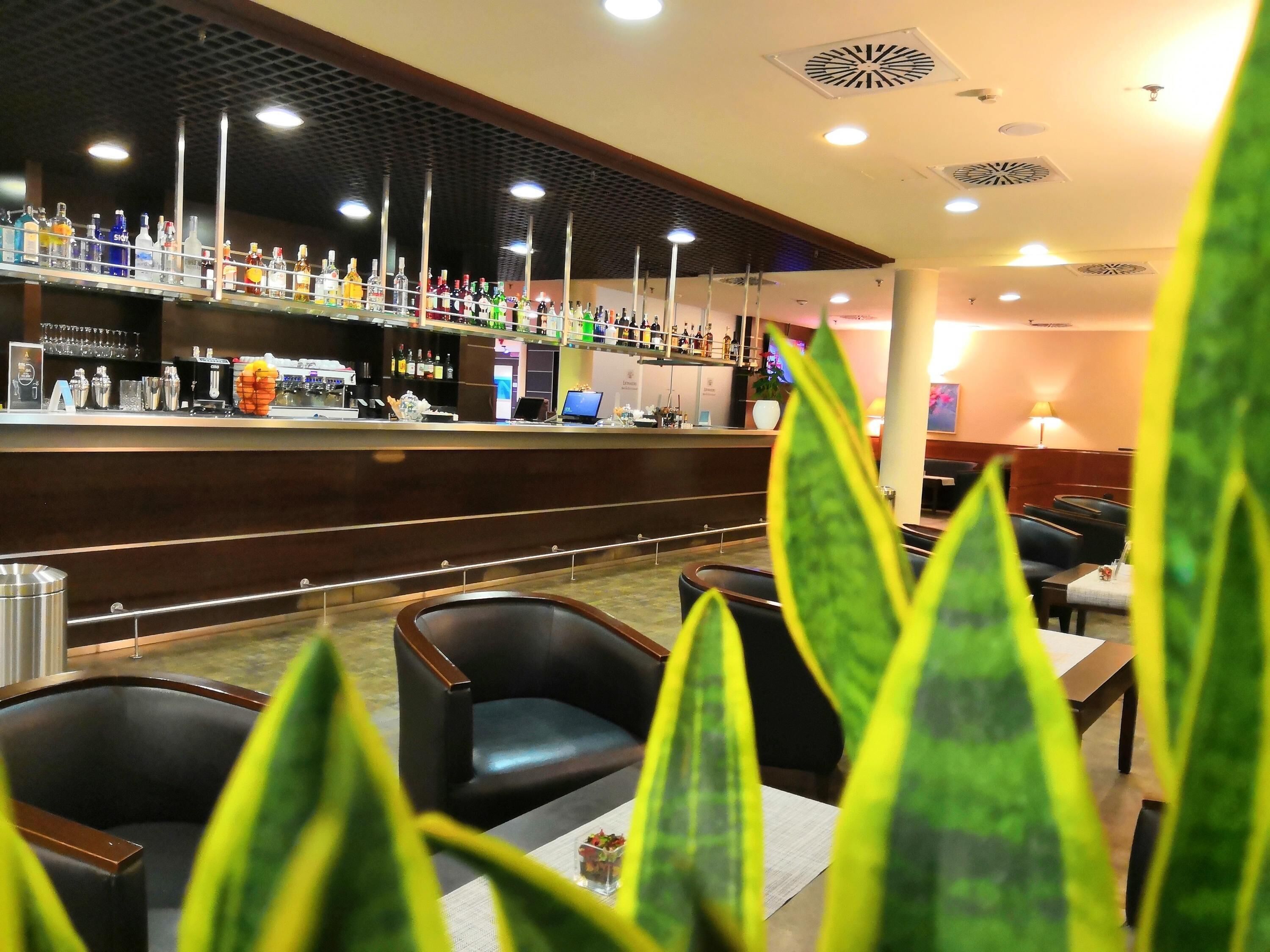 A bar area with a variety of liquor bottles, a counter with a computer, and seating with tables and chairs.