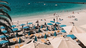 A beach with numerous sun loungers and umbrellas, a clear blue sky, and calm sea. - Princesa Yaiza Suite Hotel Resort (Yaiza)