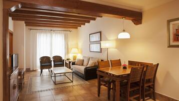 A dining area with a wooden table and chairs, a sofa, a TV, and a lamp.