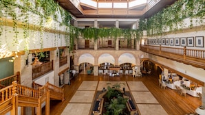 A spacious lobby with a high ceiling, wooden railings, and hanging plants. - Princesa Yaiza Suite Hotel Resort (Yaiza)