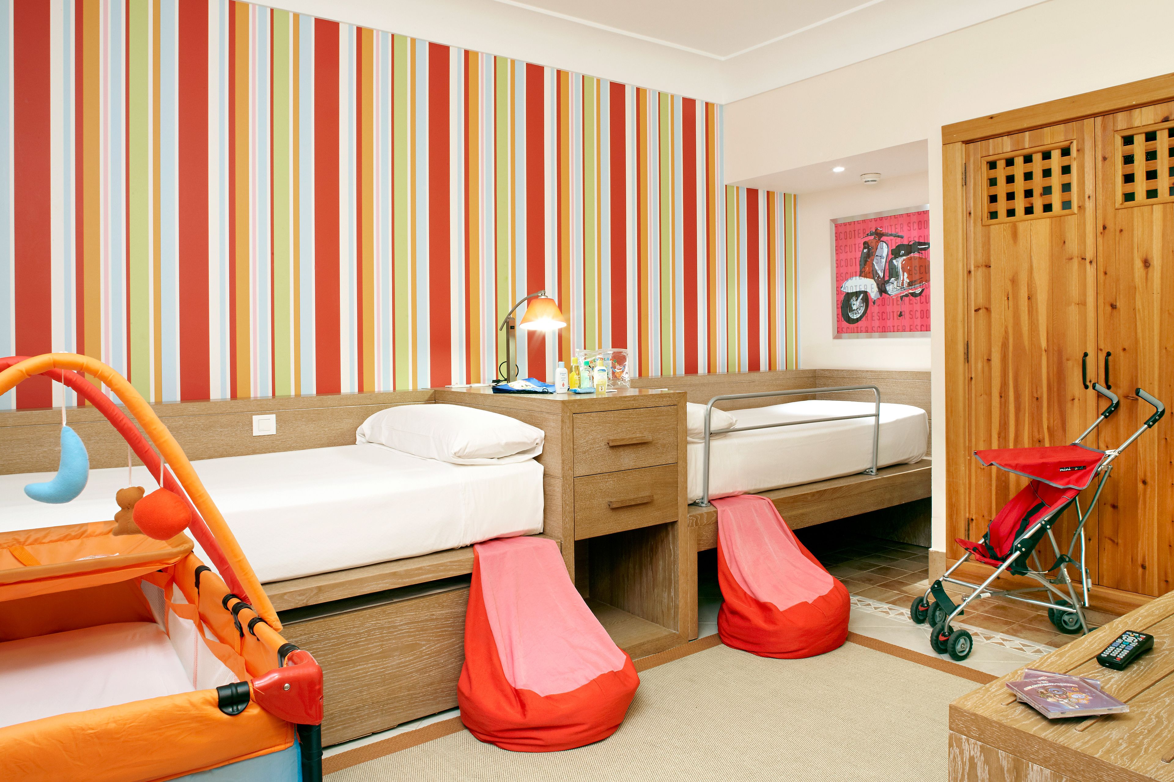 A child’s room with a bunk bed, a play area, a desk with a lamp, and a stroller.