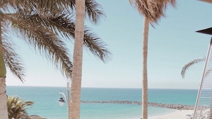 A dining table with a view of the beach and ocean, surrounded by palm trees. - Princesa Yaiza Suite Hotel Resort (Yaiza)