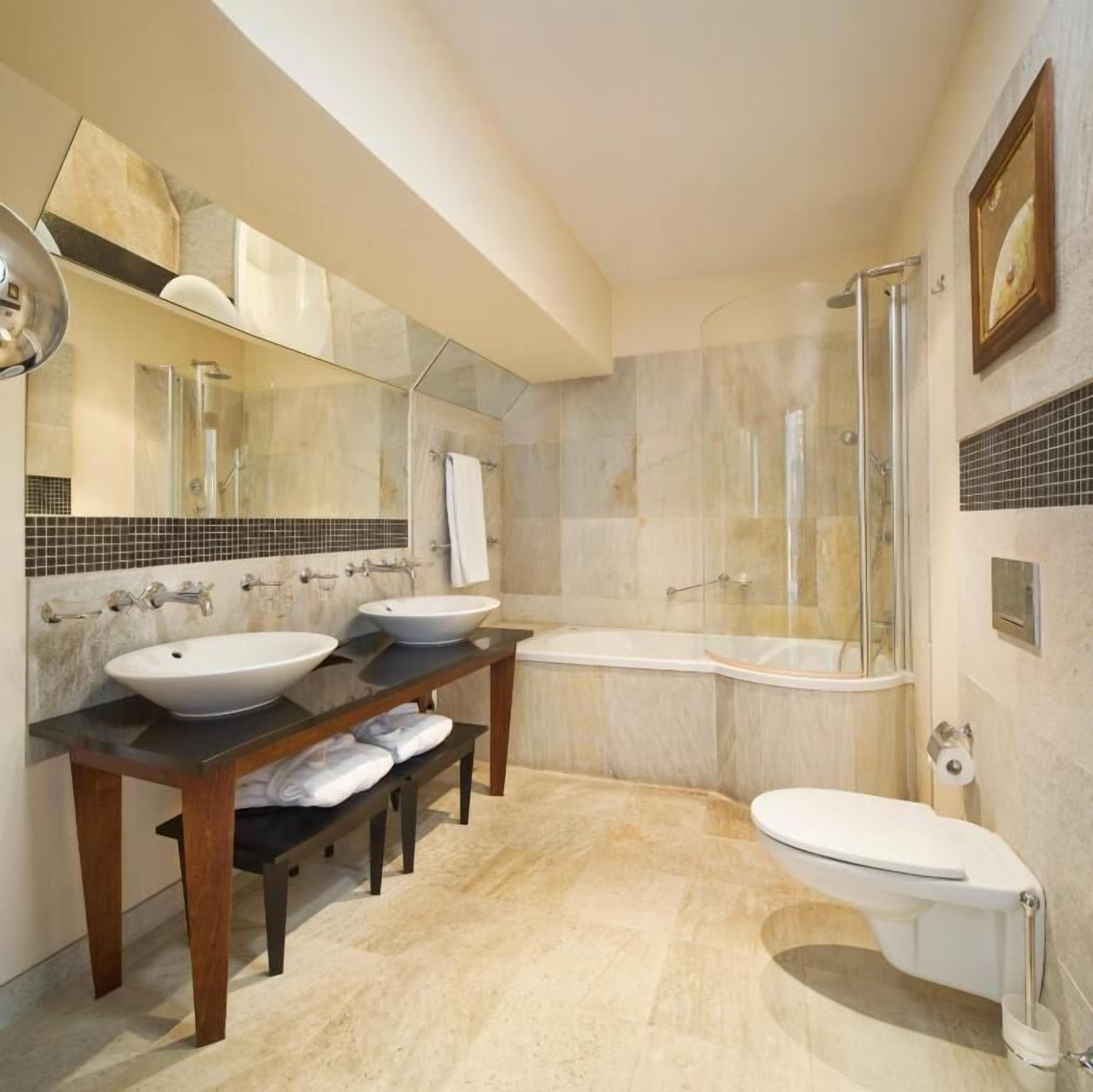 Une salle de bain moderne avec deux lavabos, une baignoire et une douche.