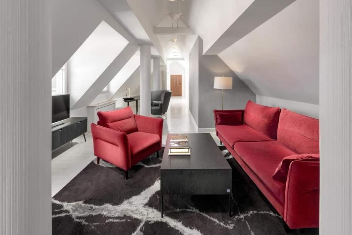 Un salon moderne avec une table basse noire, des canapés rouges et un téléviseur.