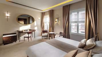 A hotel room with a large bed, a desk, a chair, a small table, and a mirror.