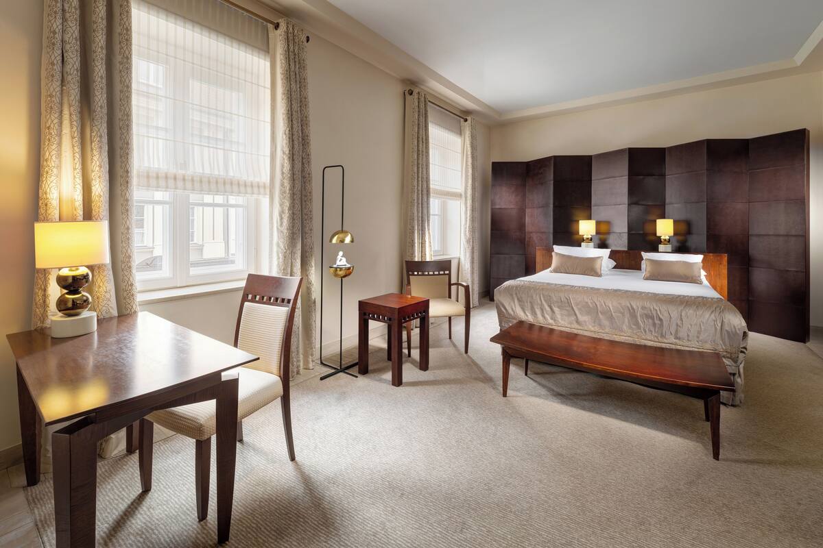Une chambre d’hôtel avec un grand lit, un bureau, une chaise, une lampe sur pied et une table de chevet.