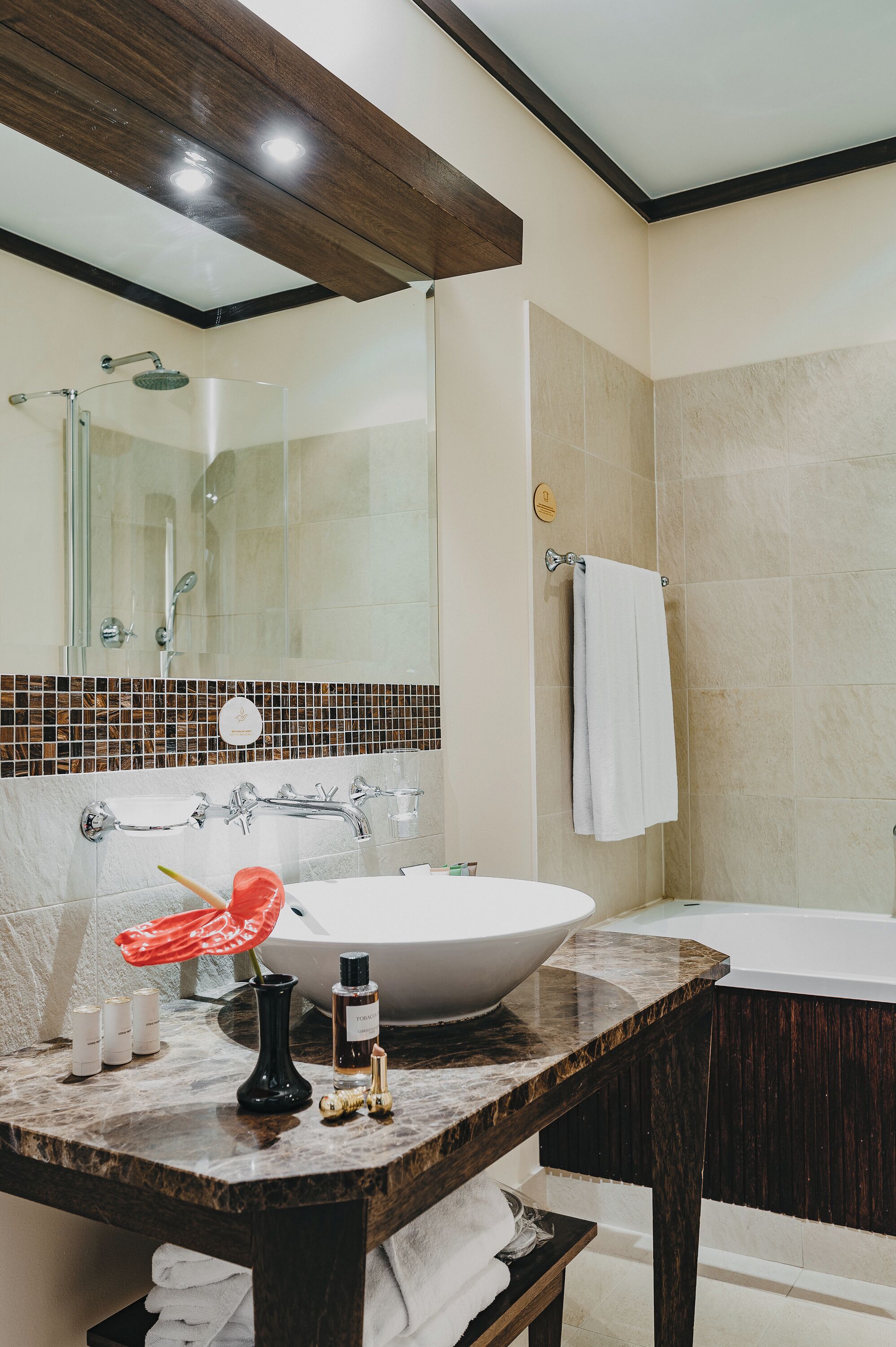 A bathroom with a large mirror, a sink with a vessel basin, a bathtub, and a shower area.