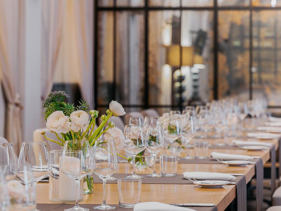 A long dining table set with white tablecloths, glassware, and floral centerpieces.
