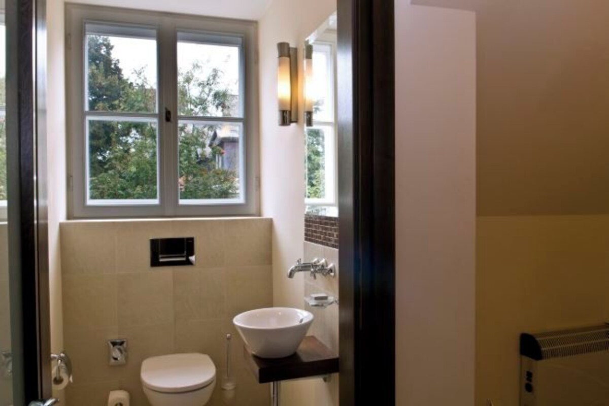 A bathroom with a toilet, sink, and window.