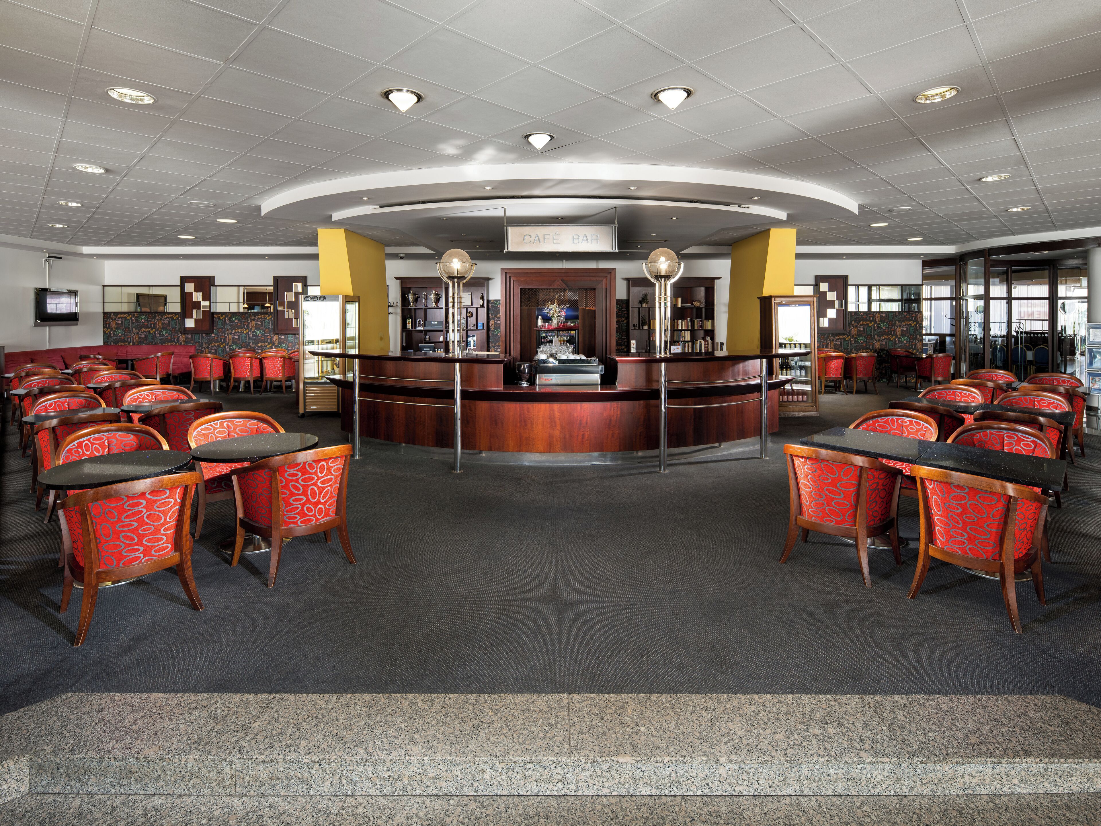 A spacious restaurant with a central bar, multiple seating areas, and a modern ceiling design.
