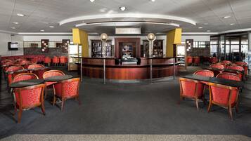 A spacious restaurant with a central bar, multiple seating areas, and a modern ceiling design.