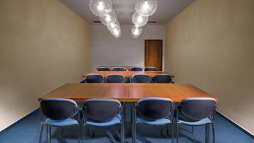 A conference room with a long wooden table, black chairs, and hanging spherical light fixtures.