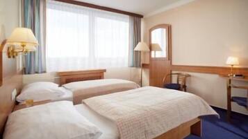 A hotel room with two beds, a desk, and a chair.