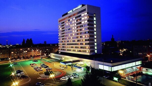 Un hotel de varios pisos con un letrero llamativo, un estacionamiento y un edificio contiguo.