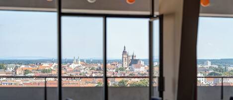 A conference room with tables and chairs, large windows offering a view of a cityscape with historic buildings.