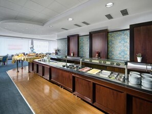 A buffet area with multiple food stations, a long counter, and a seating area with tables and chairs. - Hotel Cernigov (Hradec Kralove)