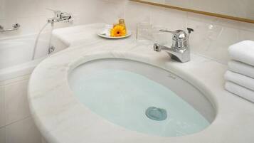 A bathroom with a marble sink, a bathtub, and a towel rack.
