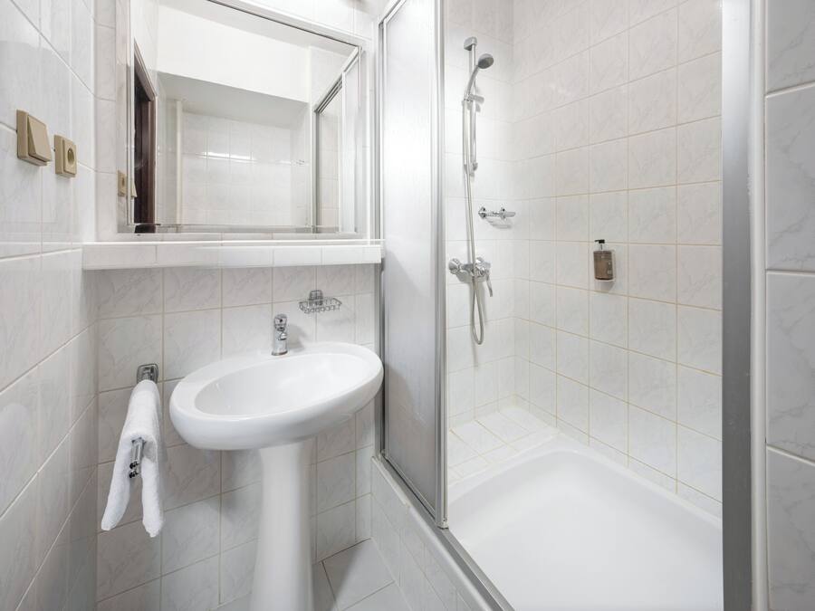 A modern bathroom with a white sink, mirror, and shower.
