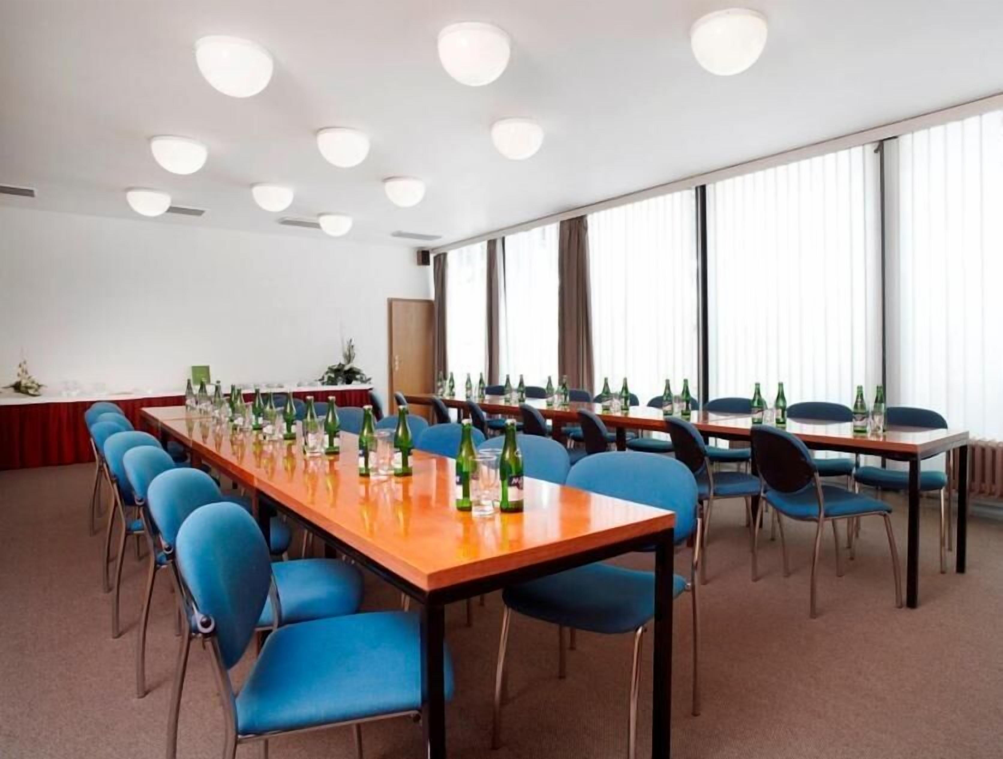 A conference room with long tables, blue chairs, and bottles of water.