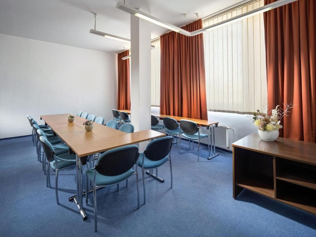 Ein Konferenzraum mit einem langen Tisch, Stühlen und einem kleinen Beistelltisch mit einer Vase.