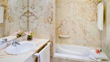 Une salle de bain avec un lavabo en marbre, une baignoire et un miroir.