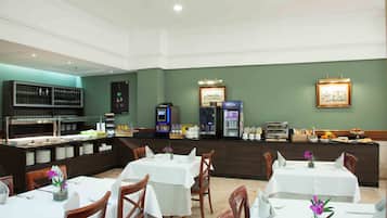 A restaurant with multiple tables, chairs, a buffet area, and a counter with various food items and condiments.