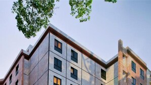 A multi-story hotel with a classic facade, large windows, and a courtyard with seating and greenery.