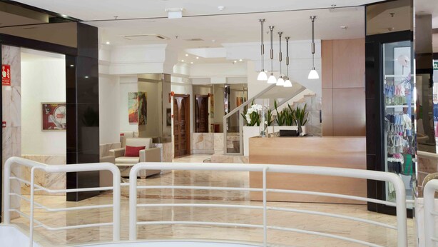 A modern interior with a marble floor, a reception area, and a staircase leading to upper floors.